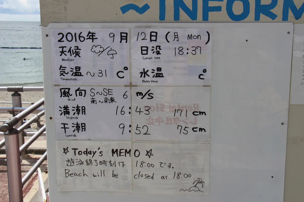 A handwritten weather board at an Okinawa beach