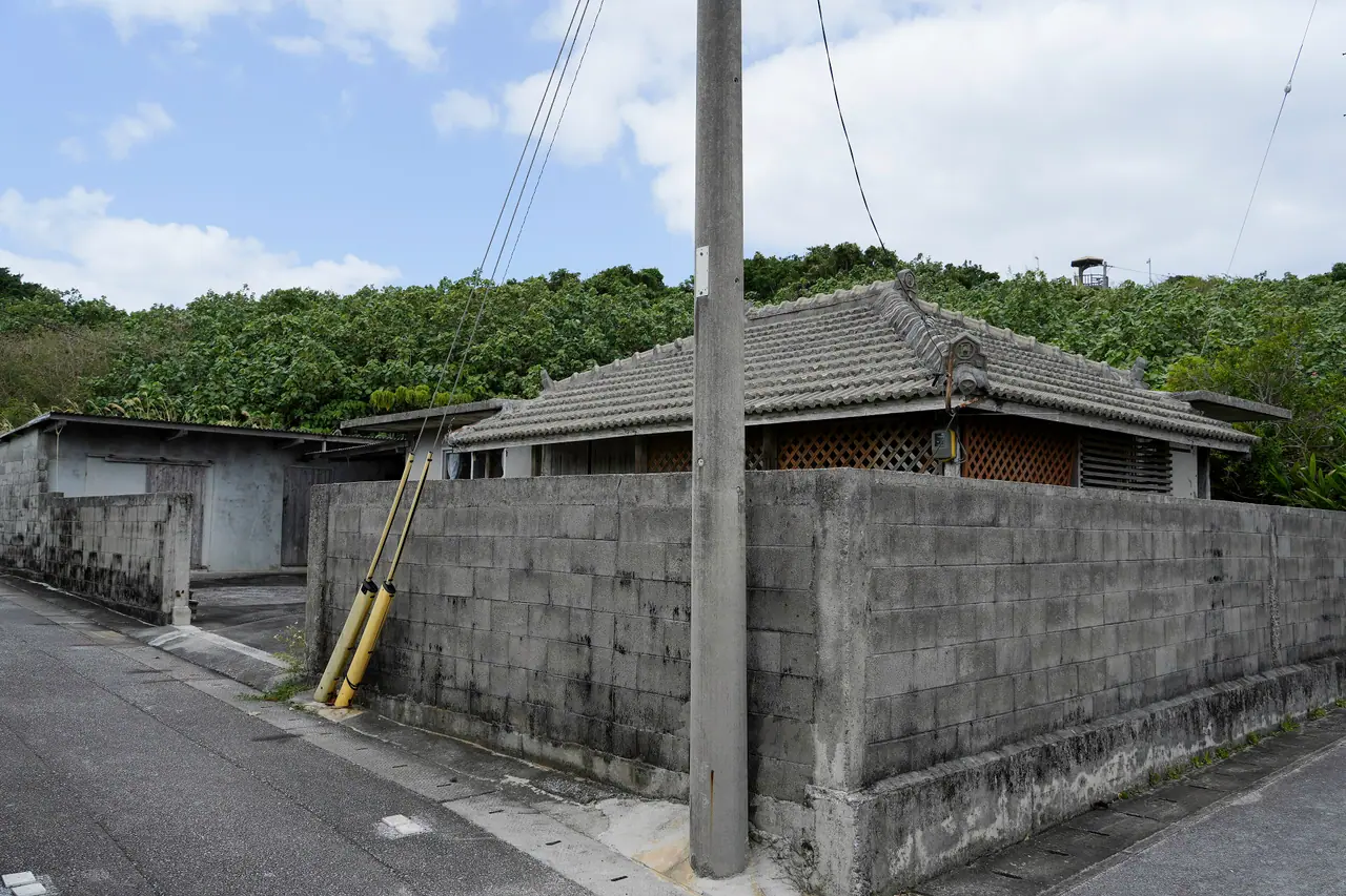 A single-storey concrete house behind a concrete-block wall