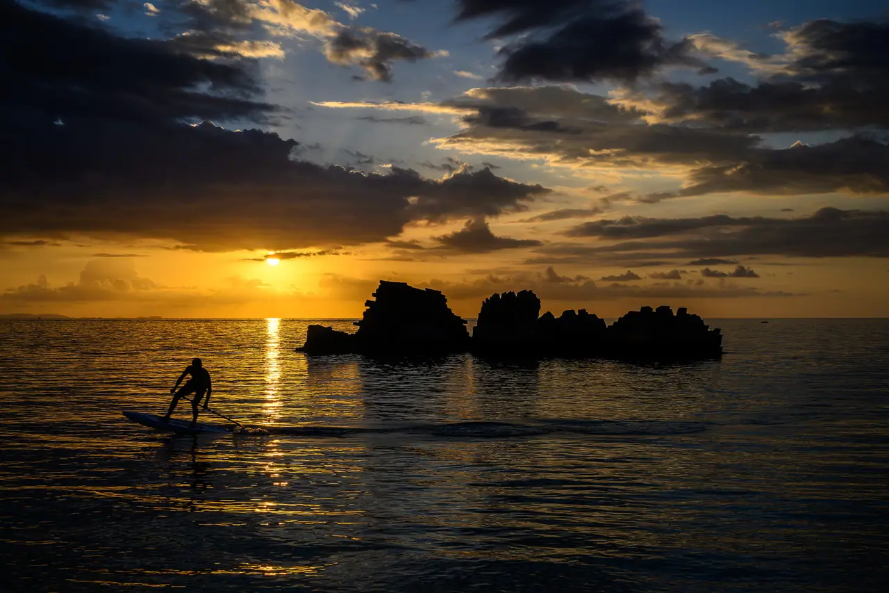 A paddleboarder silhouetted against an Okinawa sunset